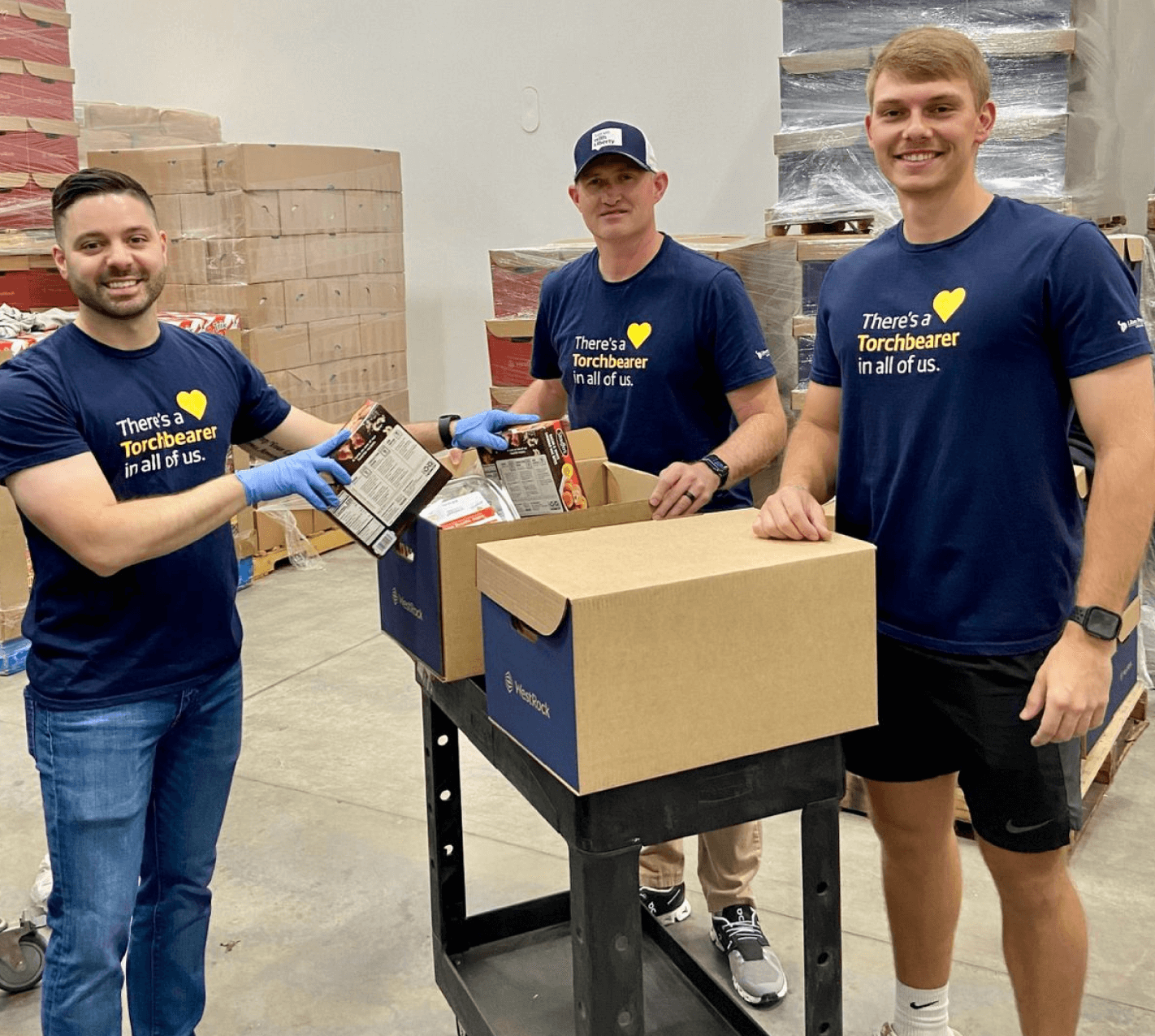 3 men volunteering with boxes of food.